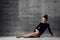 Sophisticated woman is sitting posing on a floor sexy looking at her gorgeous long legs on dark concrete wall background