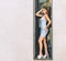 Sophisticated young woman in tight short blue dress posing standing in the recess of a rectangular glass window