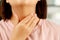 Sore throat pain. Closeup of young woman sick holding her inflamed throat using hands to touch the ill neck in blue shirt on gray