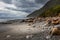 Sormy weather approaching a rock strewn beach in New Zealand