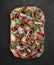 Sorrentina pizza with prosciutto, arugula, capers, pelati sauce, pesto. Roman pizza rectangular on dark background