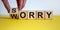 Sorry to worry. Hand turns a cube and changes the word `worry` to `sorry`. Beautiful yellow table, white background. Business