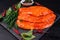 Sottilissime. Delicious dietary meat. Sottilissime in red marinade on a black stone kitchen board with a razmarin branch and