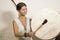 Sound healing and meditation therapy - attractive and elegant Asian Chinese healer woman playing drum at yoga studio as relaxation