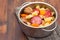 Soup chestnuts with smoked sausage in pot on wooden background
