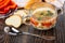 Soup with chicken meat, rice, vegetables in bowl, napkin, pieces of bread, saucer with sweet pepper, spoon on table