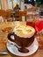 Soup in clay bowl with beverages served on wooden table