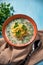 Soup with egg noodles and fresh herbs in an orange soup bowl. Seasoned with chopped dill, black pepper, parsley leaves. Parsley