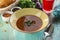 Soup with meat and beans with parsley and glass of red drink on blue wooden table