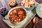 Soup with meat, oregano, chickpeas, peppers and vegetables served with crackers and bread on plate