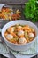 soup with meatballs, pasta, peas and parsley on a wood table