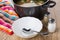 Soup in pan, white plate, salt pepper, spoon and napkin