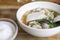 Soup with pock, pock stick, mushroom, vegetable in white bowl near have rice in small bowl on wood table. with copy space for text