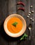 Soup puree of carrot, pepper, greens, vintage spoon on a wooden background, top view