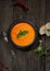 Soup puree of carrot, pepper, greens, vintage spoon on a wooden background, top view