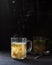 Soup in a transparent mug with curly pasta, for a child. A dark photo.