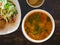 Sour and spicy Tom Yum Goong soup and salad with green mango and breaded fish on plate on a table in a restaurant. Thai Authentic