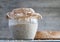 Sourdough on whole grain flour in glass jar and loaf rye bread on table, yeast-free leaven starter for organic bread