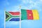 South Africa and Cameroon two flags on flagpoles and blue sky