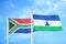 South Africa and Lesotho two flags on flagpoles and blue sky