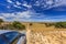 South Australian landscape with hills and meadows with shrubs and dirt road against blue sky with clouds veil