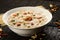 South Indian sweet pudding Kheer in a white bowl in a dark wooden background.