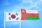 South Korea and Oman two flags on flagpoles and blue cloudy sky