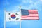 South Korea and United States two flags on flagpoles and blue cloudy sky