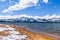 South Lake Tahoe shoreline and snow covered sandy beach, on a sunny day; the snow covered Sierra mountains in the background;