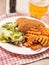 Southern fried chicken fillet meal with green fresh salad and fancy cut potato chips served on white plate and glass of lager beer