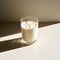 Soy milk in the glass on white background with shadow of sun in morning sun light