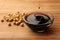 Soy sauce drops falling into bowl and soybeans on bamboo mat, closeup