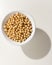 Soybean legume. Grains in a bowl. Shadow over white table.