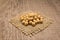 Soybean legume. Grains on square cutout of jute. Wooden table. S