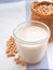 Soymilk in a glass with a sackcloth bag on a white dishcloth with blue straight stripes background.