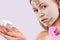 Spa and beauty concept. Young woman, girl, lady with perfect smooth, clean skin with facial clay mask shows a glass jar