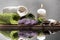 Spa. Burning candle surrounded by pebbles, flower, towels on wooden table.