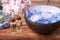 Spa composition. Aromatic water in bowl, bottles of essential oil and flowers on wooden table, closeup
