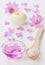 Spa composition with sea salt bath in wooden spoon, pink flowers petals and burning candle on a white surface