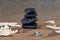 Spa composition - stacked Basalt Stones, Seashells and Sea Stars on the beach at sunrise in front of the ocean.