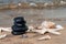 Spa composition - stacked Basalt Stones, Seashells and Sea Stars on the beach at sunrise in front of the ocean.