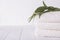 Spa composition on wooden table. Stack of three white fluffy bath towels with eucalyptus branch.