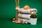 Spa essentials, candle, stones, towel and flowers on a dark green background