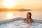 Spa hotel luxury relax jacuzzi therapy pool Asian woman relaxing in resort hot tub outside on private room balcony sunset over sea
