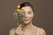 Spa model woman with perfect clear skin and flowers on brown background. Eyes closed. Herbal medicine and skincare concept