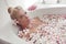 Spa Relax. Blonde enjoying bath with plumeria tropical flowers. Health And Beauty. Closeup Beautiful Sexy Girl Bathing With Petals