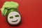 Spa salon - cheerful friendly cartoon. Relaxed happy green ripe juicy pear with white cosmetic mask and light green towel on red b