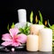 spa setting of hibiscus flower, twig bamboo, thai herbal compress balls, beads and candles on zen basalt stones with drops, close