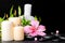 spa setting of hibiscus flower, twig bamboo, thai herbal compress balls, beads and candles on zen basalt stones with drops, close