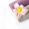 Spa setting of towel, pink flower isolated on white. Copy space. Square image.